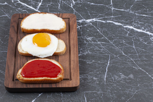 可口把鸡蛋 果酱和奶酪分别放在木板上的面包片上 放在大理石表面烘焙烘焙食品面包