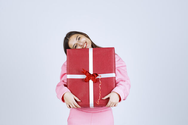 人类穿着粉色睡衣的女孩抱着一个大大的红色礼盒 微笑着女人人类服装