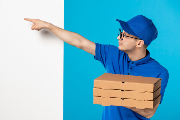 盒子身穿蓝色制服的男快递员的正面图 蓝色的是披萨盒头饰服务帽子