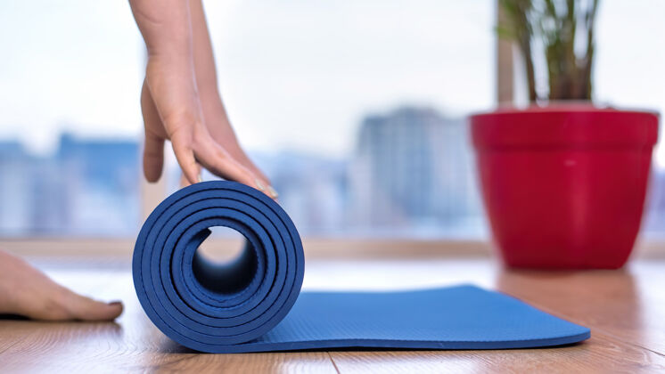 女人女人在家里放松一个蓝色的瑜伽垫训练垫子瑜伽运动