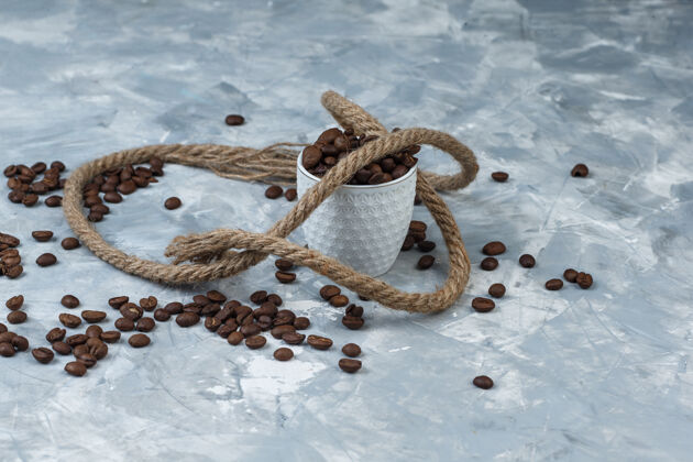 摩卡咖啡咖啡豆在一个白色的杯子里 在灰色的石膏背景上用绳子高角度观看食物配料热的