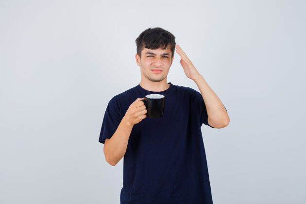 怀疑年轻人端着一杯茶 举着一只手 穿着黑色t恤衫 面带疑惑地看着前方发型成人手