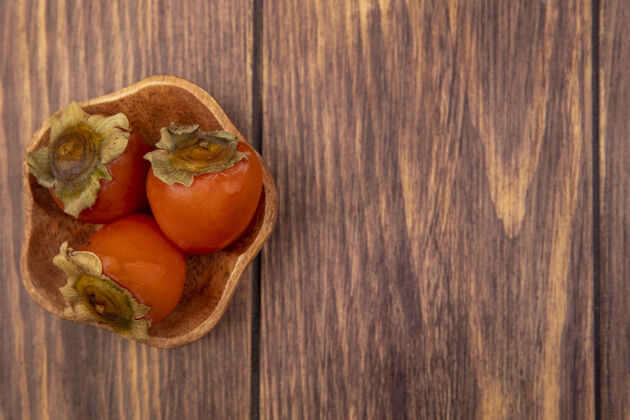 美味熟透的松软多汁的柿子的顶视图放在一个木制的碗上 有复印空间柿子午餐新鲜