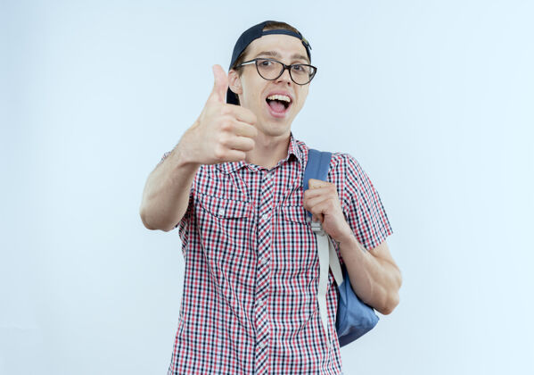 男人快乐的年轻学生男孩戴着背包和眼镜 戴着大拇指穿年轻人学生