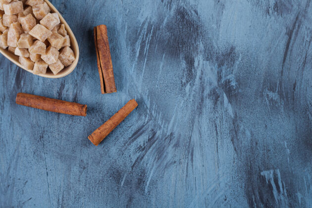 肉桂一碗红糖块和肉桂棒放在蓝色的表面上立方体壁板食品