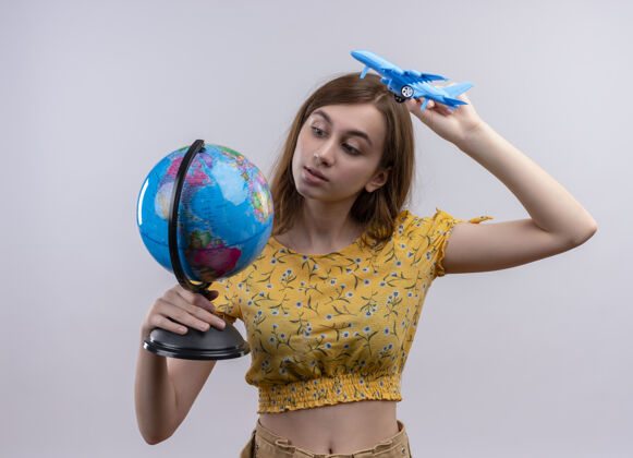 模特年轻女孩拿着地球仪和飞机模型 看着孤零零的白墙上的地球仪女孩抱着女人