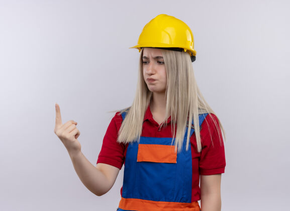建筑工人一个穿着制服的年轻金发建筑工女孩 拿着一只手在孤立的白墙上看着它年轻人金发表演