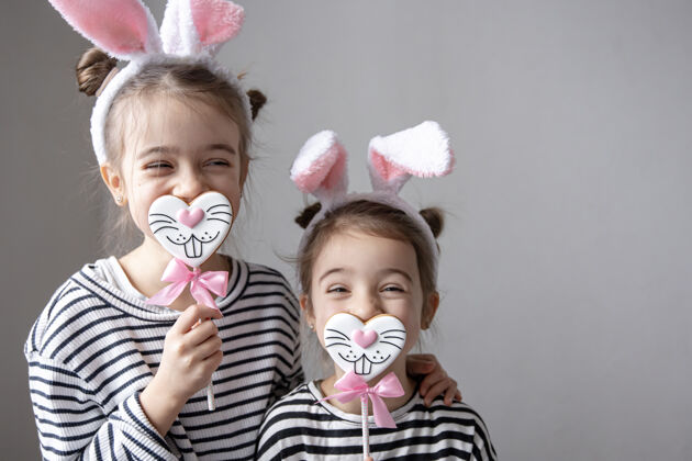 年轻可爱的小姐妹们 带着复活节姜饼 兔子脸和兔子耳朵甜点人复活节