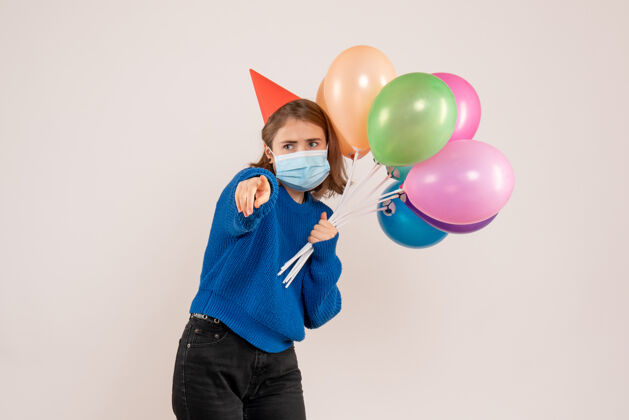 看法戴着白色面具手持彩色气球的年轻女性生日庆祝情感