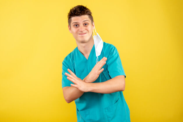 高尔夫球手正面图身着医疗服的年轻男医生 黄色背景上有无菌面罩健康绝育医学