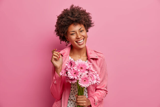 美国年轻开朗的非洲裔美国女性 妆容自然 笑容灿烂 手持花束 向朋友道贺 享受非洲菊的宜人气味种族女性芳香