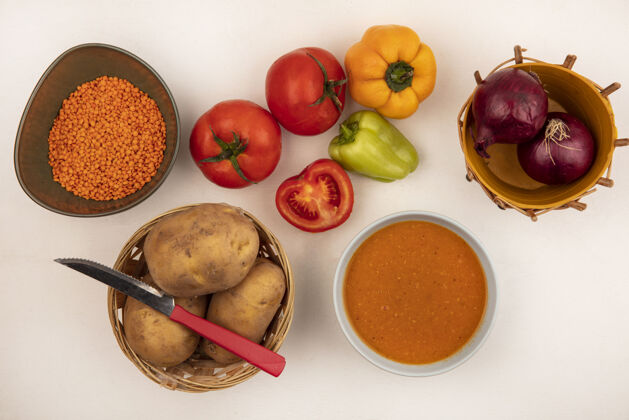 木头一碗营养扁豆汤的俯视图 红洋葱放在桶上 土豆放在桶上 小刀把辣椒和西红柿隔离在白色的墙上饮食景食物
