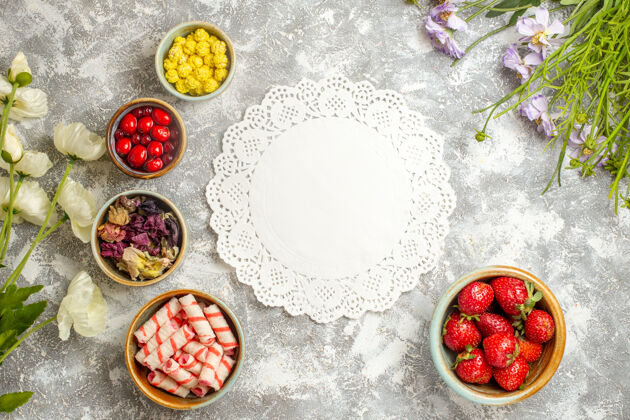 胡椒粉顶视图新鲜的红色草莓和糖果在白色地板上的颜色浆果糖果午餐颜色饮食