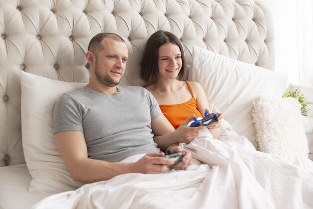 视频游戏夫妻俩在床上玩电子游戏操纵杆技术娱乐