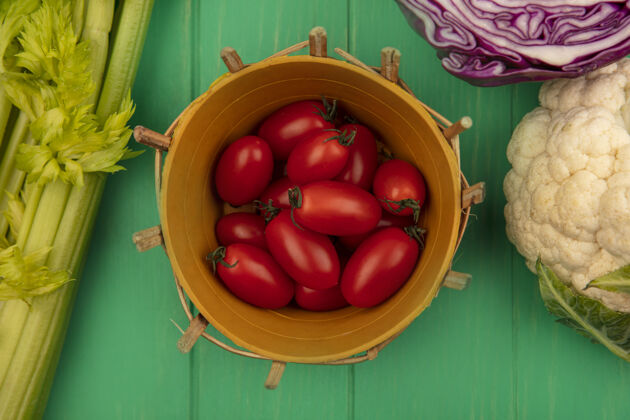 食品一桶红梅西红柿的顶视图 紫色卷心菜菜花和芹菜被隔离在绿色的木墙上桶农业芹菜