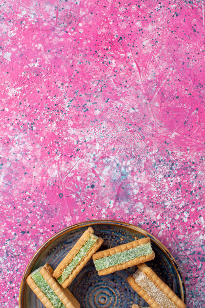 生的美味的华夫饼干在粉红色表面盘子里的顶视图美味表面糖