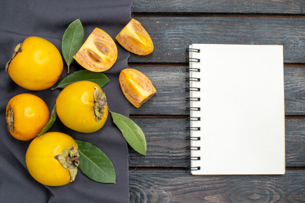 农业顶视图新鲜甜甜的柿子放在木质质朴的桌子上 果实醇厚笔记本黄色木材