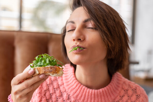 盘子一位女士穿着一件温暖舒适的毛衣在一家餐厅享用健康的早餐 烤面包配芝麻菜和三文鱼乡村面包吐司