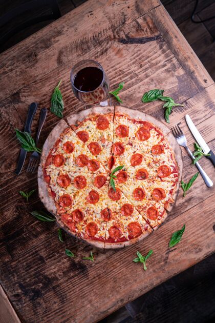 自制垂直拍摄美味的芝士意大利香肠比萨和一杯葡萄酒放在木桌上美味餐具比萨饼