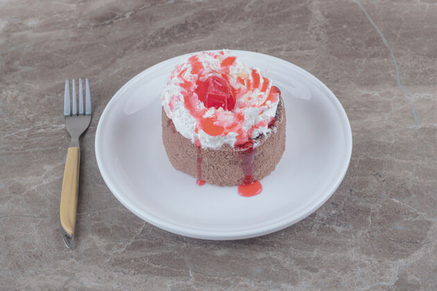 烘焙一个小蛋糕 上面放着奶油和草莓糖浆 放在大理石盘子上糖浆口感蛋糕