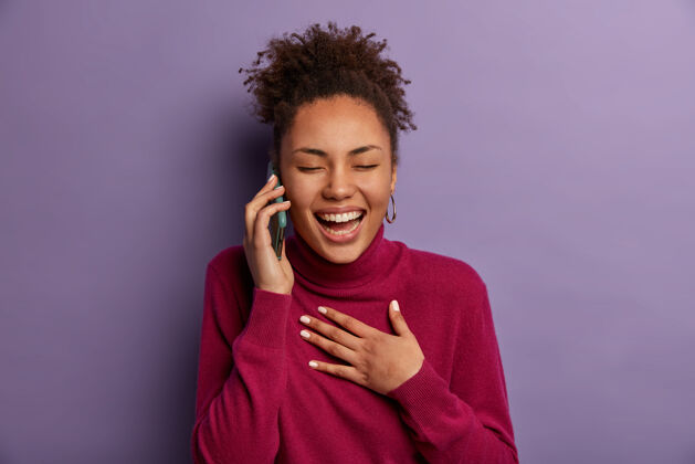 女孩沟通 人和技术概念非洲裔美国妇女在讲手机时无忧无虑地笑 闭上眼睛 不停地笑 从朋友那里听到一些有趣或非常积极的事情积极人美国