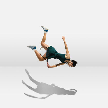 美丽年轻的职业女运动员悬浮在空中 一边打网球一边在白墙上孤立游戏动作专业