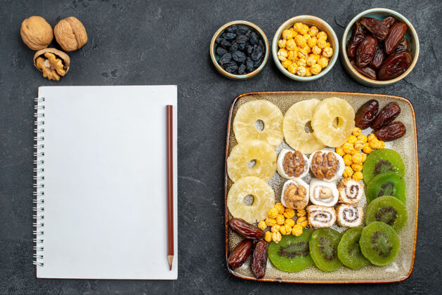食物顶视图切片干果菠萝戒指和猕猴桃灰桌干果葡萄干甜维生素酸健康托盘晚餐容器