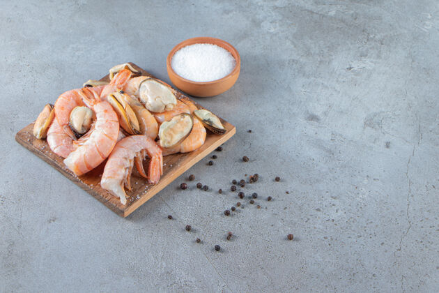 皮把贻贝和对虾放在盐旁边的木板上 放在大理石背景上盐板好吃的