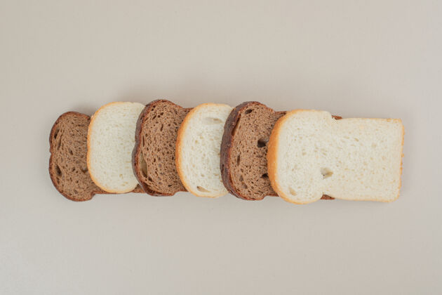 脆把新鲜的白面包和棕色面包切片放在白色的表面上切面包切片