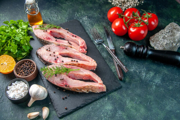 晚餐前视图新鲜鱼片与绿色和西红柿对深蓝色表面海鲜沙拉餐海洋晚餐颜色生肉水照片番茄沙拉海鲜