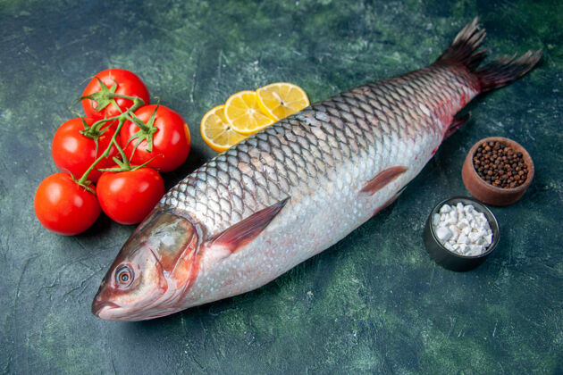 切片正面图新鲜生鱼片配西红柿和柠檬片 深蓝色表面鲨鱼海鲜餐海洋肉类横向晚餐食物颜色动物水柠檬鱼食品海洋