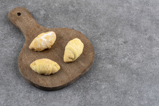 面包皮大理石桌上放着三块新鲜饼干的木板面包房松脆烘焙