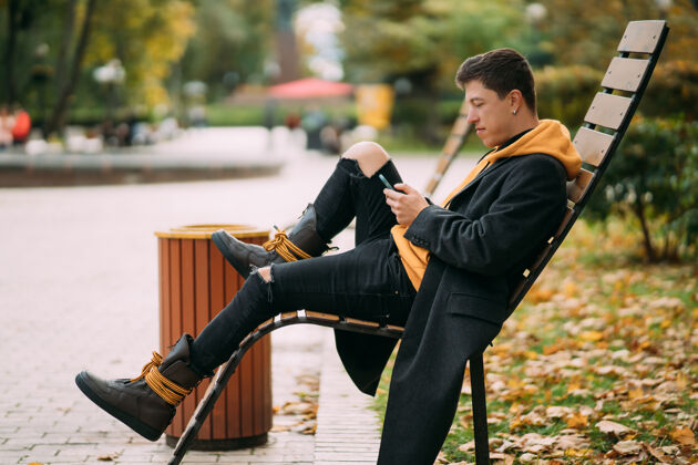 白种人坐在公园长椅上听音乐的年轻人坐着男人叶子