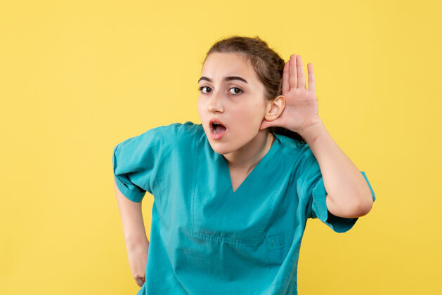 护士身穿医用衬衫的年轻女医生在黄色墙壁上聆听的正视图病毒衬衫疾病