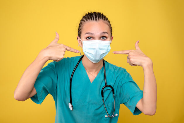 女医生黄色墙壁上戴着无菌防护面具的女医生的正视图消毒健康医疗器械
