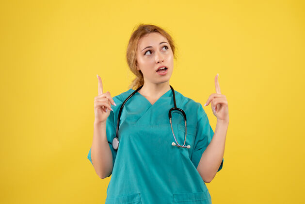 医疗器械黄色墙上穿着带听诊器的医疗服的女医生的正视图护士健康医院