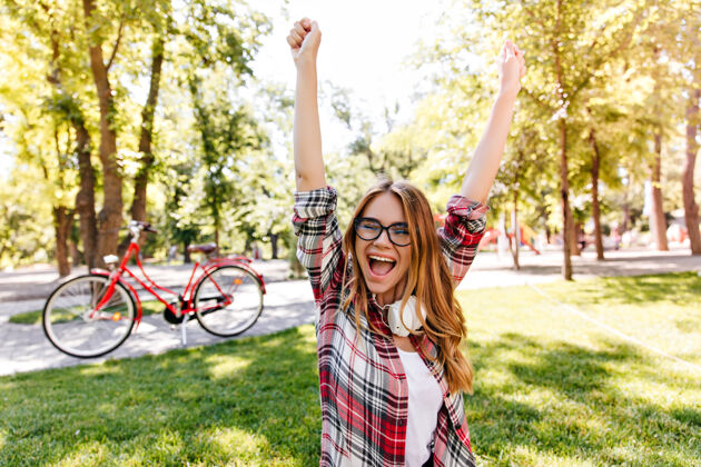 自行车可爱的年轻女子在公园里表达激动的情绪高兴的欧洲女孩在户外穿格子衬衫美丽行动微笑