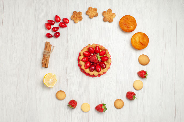 框架在白色的桌子上俯瞰带有水果和蛋糕的小饼干水果形状花