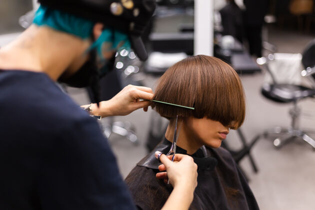 流行一个专业的女理发师给客户理发这个女孩戴着面具坐在美容院里顾客发廊脸