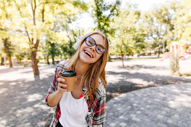 乐趣戴着眼镜的快乐白人女孩在公园里表达积极的情绪高加索女士喜欢户外活动夏天金发卷发