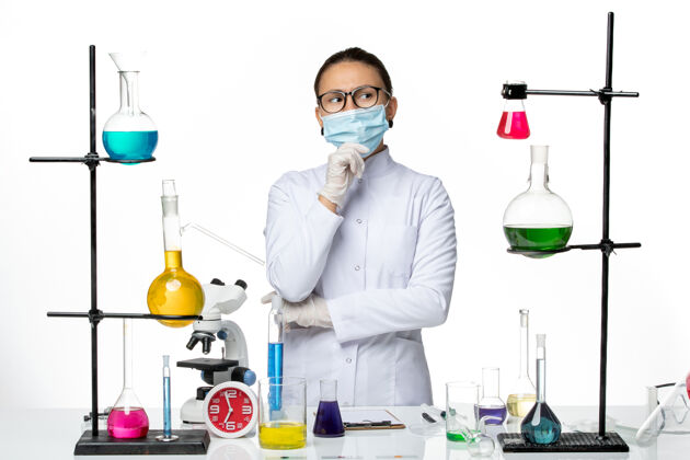 实验室前视图：戴着口罩的女化学家在白色背景上思考病毒化学实验室病毒-飞溅医学医学外套