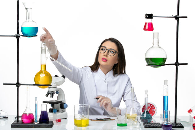 视图前视图穿着白色医疗服的女化学家正坐在一个白色背景的科维德科学大流行实验室病毒的解决方案人成人大流行