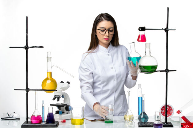 大流行前视图穿着无菌医疗服的女化学家拿着装有白色背景病毒冠状病毒溶液的烧瓶-大流行科学容器烧瓶罐子