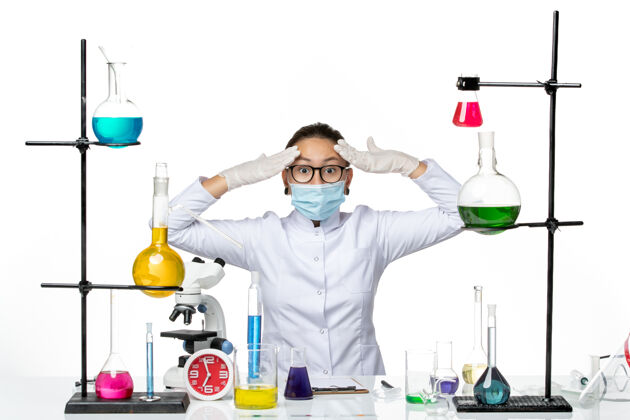 飞溅前视图穿着医疗服的女化学家 带着面罩坐在桌子前面 白色背景上有溶液病毒化学实验室的covidsplash解决方案实验室前面