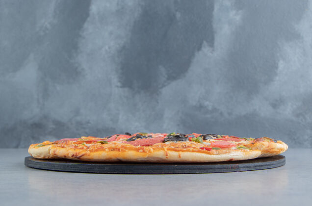 美味在大理石上的黑木板上切比萨饼香肠比萨饼快餐