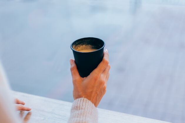 冷一个女孩在舒适的咖啡馆里用一杯热咖啡取暖马克杯成人咖啡馆