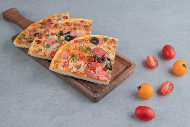 比萨饼比萨片放在托盘上 旁边是大理石上的小西红柿面包皮晚餐风味