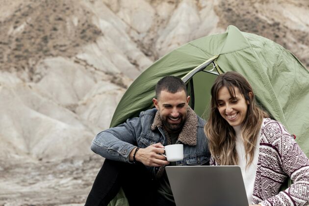 旅行者带笔记本电脑和咖啡杯的中镜头人群帐篷旅行女人