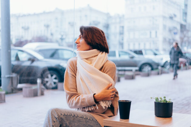 马克杯一个女孩在舒适的咖啡馆里用一杯热咖啡取暖时尚成人杯子