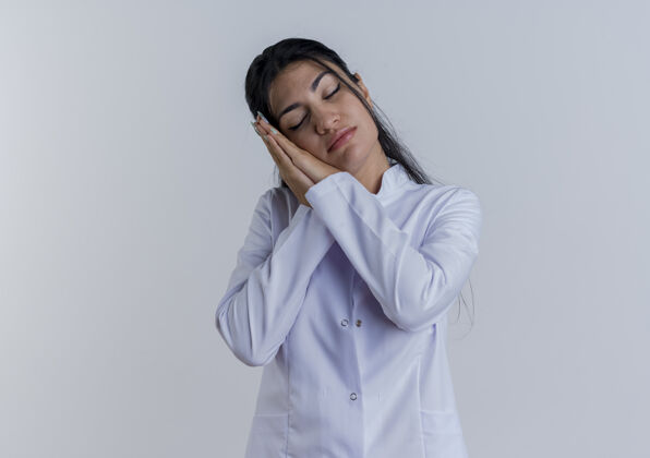 医学疲惫不堪的年轻女医生穿着医用长袍做着闭眼睡觉的姿势穿手势成人